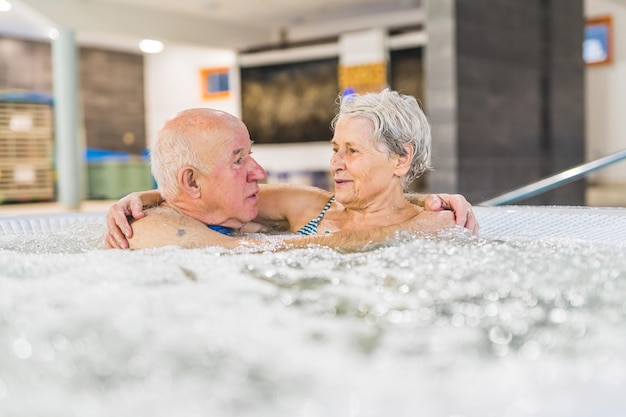 高齢のカップルが互いに手をつないで熱い風呂のウェルネスコンセプトで話し合っています