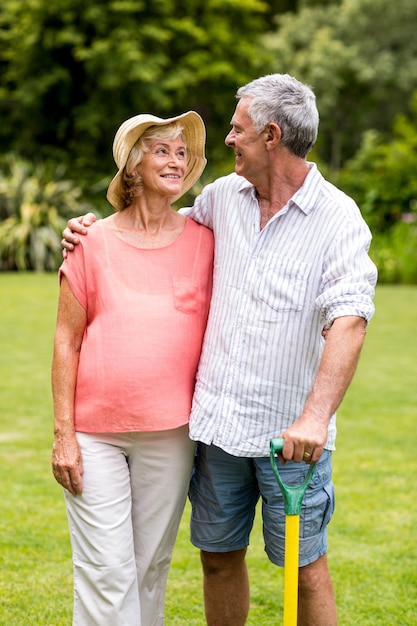 Senior couple holding rake while standing in yard