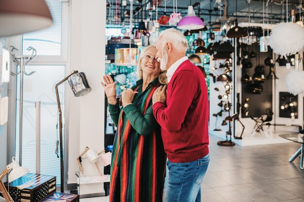 Senior couple in home lighting store shoosing shandelier for their home