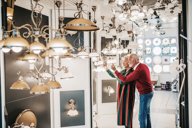 Senior couple in home lighting store shoosing shandelier for their home