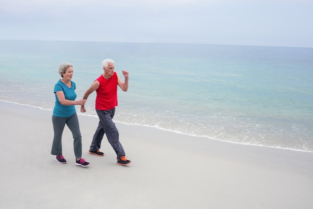 年配のカップルがビーチでジョギング