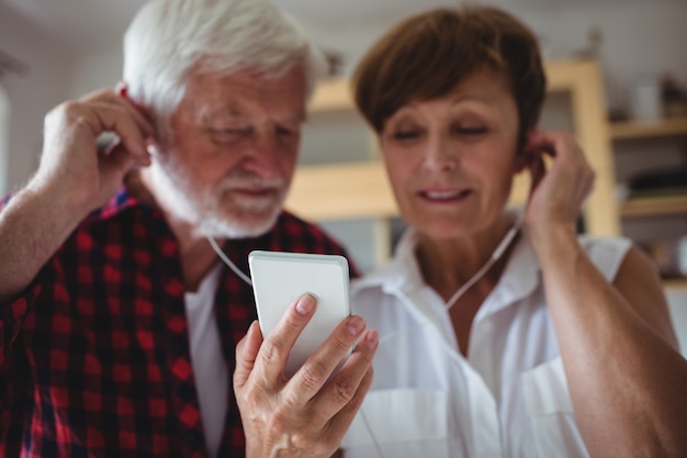 Senior couple listening to music on smartphone