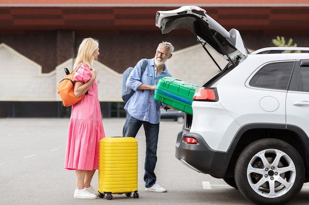 Photo senior couple loading luggage into car trunk