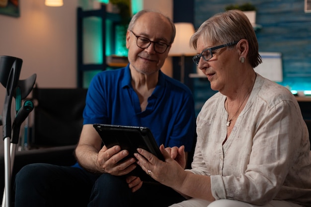 Senior couple looking at digital tablet in living room