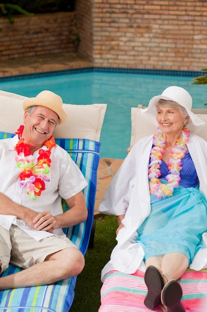 Senior couple lying down beside the  swimming pool