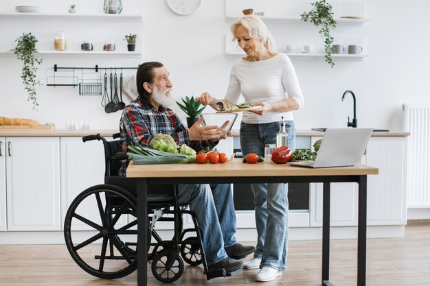 Foto una coppia di anziani in sedia a rotelle e una donna anziana che fanno un'insalata sana