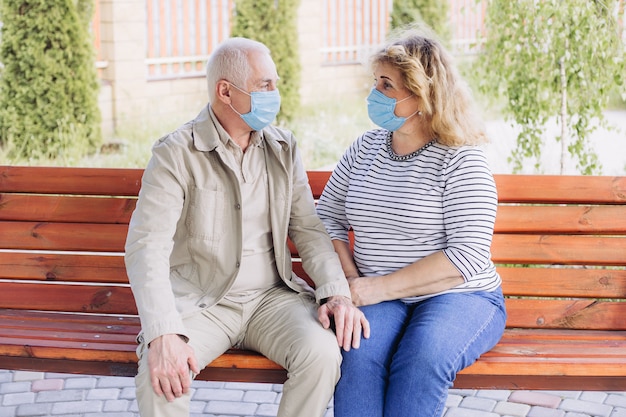 Senior couple in masks in nature, coronavirus quarantine