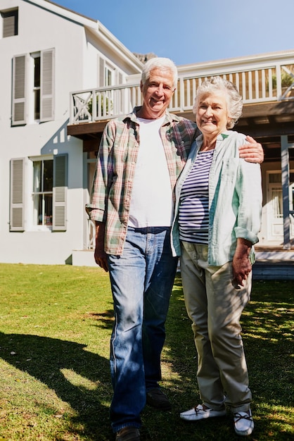 Senior couple new home and hug on grass or outdoors celebrating property or mortgage together Elderly partners and outside house or moving in real estate or security for retired homeowners