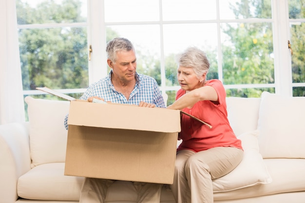 Senior couple opening big box in living room