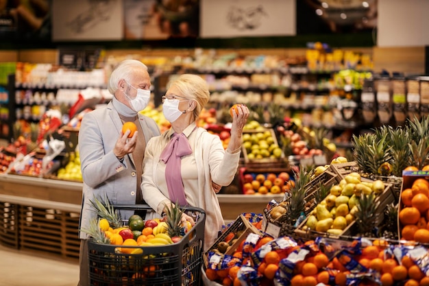 A senior couple during pandemic purchasing fruits at the supermarket