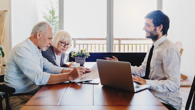 Photo senior couple planning their investments with financial advisor in living room at home