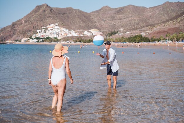 Senior couple playing on the beach and having fun on a sunny day outdoors Concept tranquility retirement enjoying