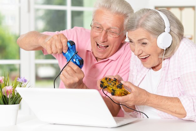 Senior couple portrait playing on laptop at home