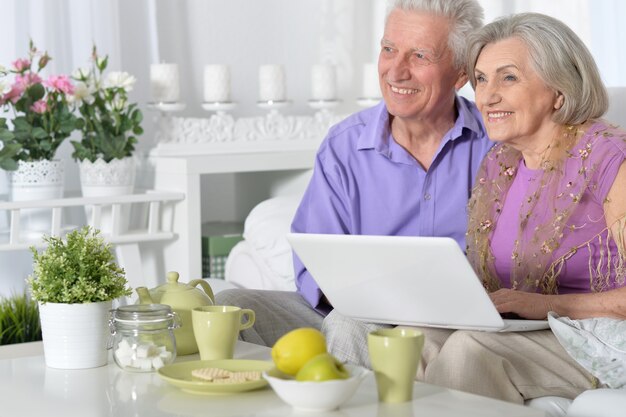 Портрет старшей пары с ноутбуком дома