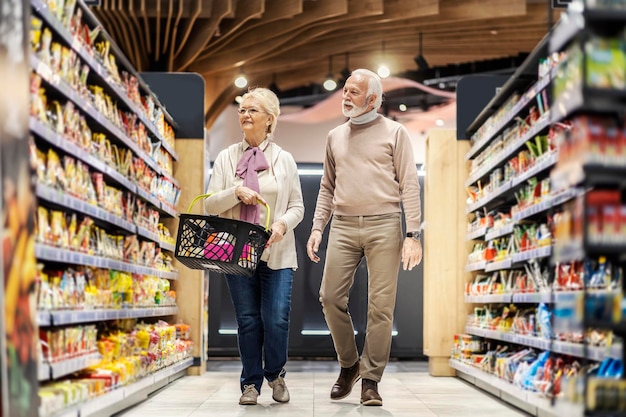 A senior couple purchases groceries at supermarket