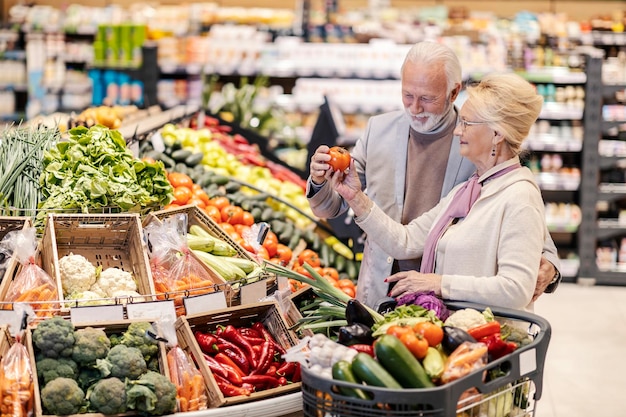 A senior couple purchasing vegetables at supermarket