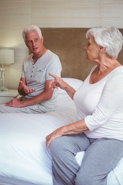 Senior couple quarreling while sitting on bed