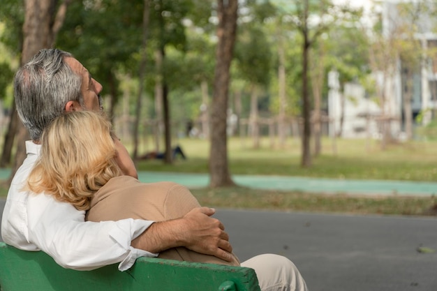 Senior couple relax sitting on bench in the park together