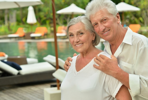Senior couple relaxing near pool at hotel resort