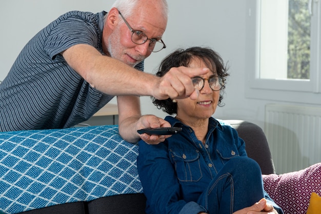 Senior couple relaxing on a sofa and watching tv at home