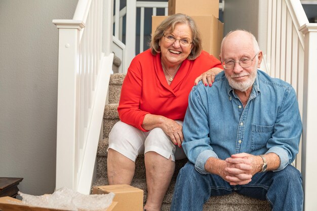 Senior Couple Resting On Stairs Surrounded By Moving Boxes