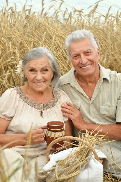 Senior couple resting at summer field with milk in jug