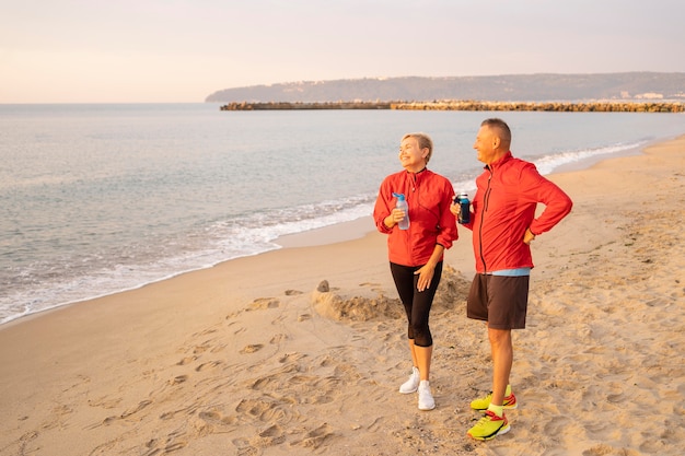 Coppia senior in appoggio mentre faceva jogging sulla spiaggia