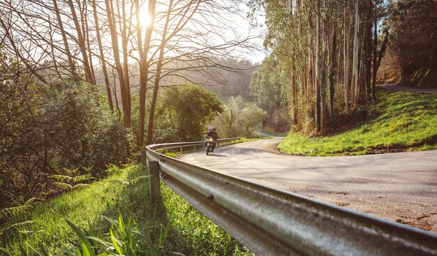 Senior couple riding a motorbike along forest road in autumn