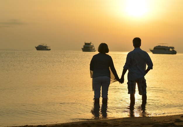 Senior couple at sea at sunset looking on boats