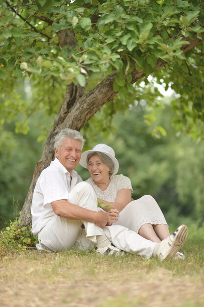 Senior couple sit on a ground in summer forest