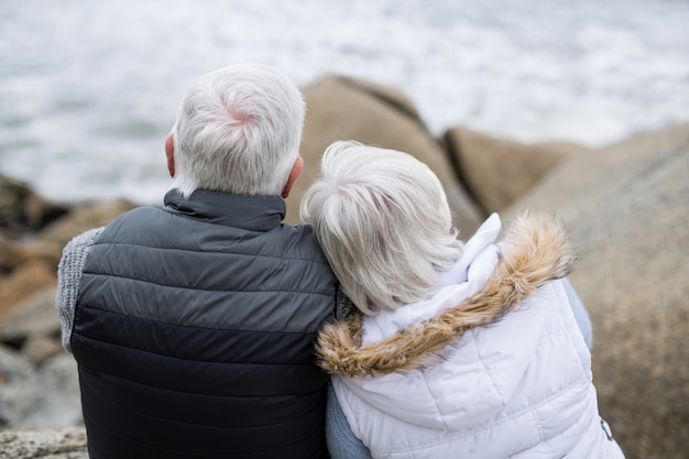 Senior couple sitting on rock at beach