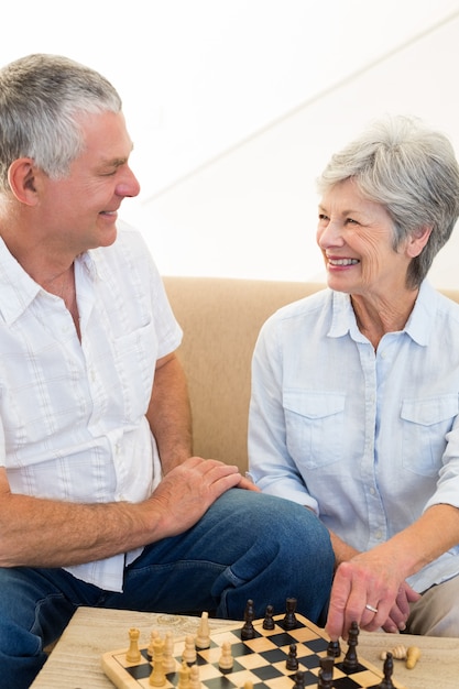 Senior couple sitting on sofa playing chess