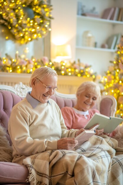 Senior couple sitting on a sofa and reading books