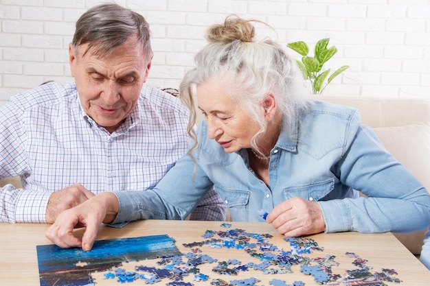 Foto una coppia di anziani che risolve un puzzle insieme a casa