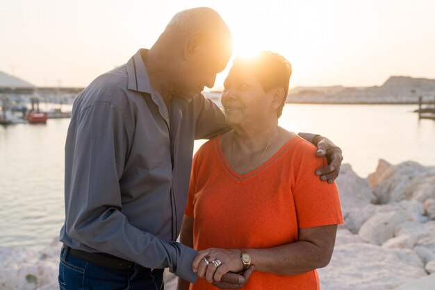 Senior couple standing at the beach together hugging