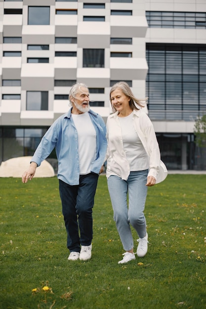 Coppia senior in piedi su un prato in estate e tenendosi per mano