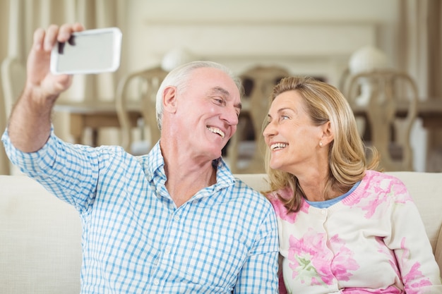 Coppie senior che prendono un selfie sul telefono cellulare in salone