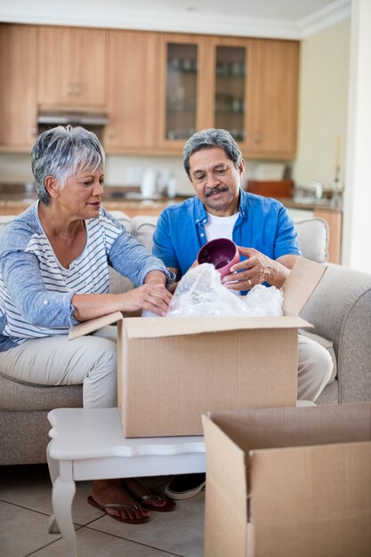 Senior couple unpackaging cardboard box in living room