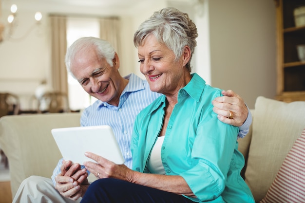 Пожилая пара с помощью цифрового планшета в гостиной