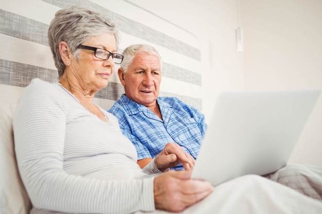 Senior couple using laptop in bedroom