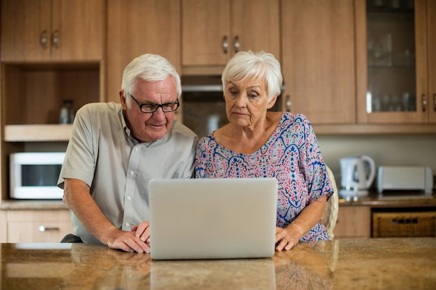 Senior couple using laptop in the kitchen at home