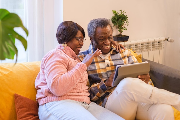 Пожилая пара, использующая планшет и весело проводящая день в Интернете, концепция комфорта для пожилых людей