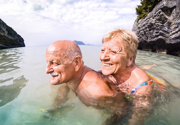 タイの熱帯のビーチで本物の遊び心のある楽しい年配のカップル行楽客