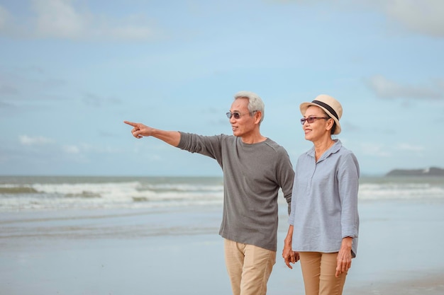 Senior couple walking on the beach holding hands at sunset, plan life insurance at retirement concept.