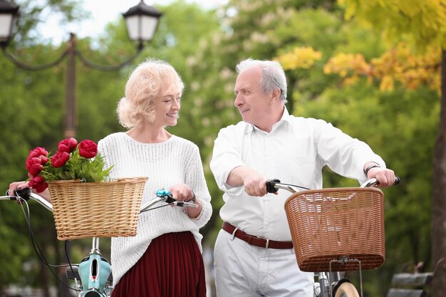 Senior couple walking with bicycles in spring park