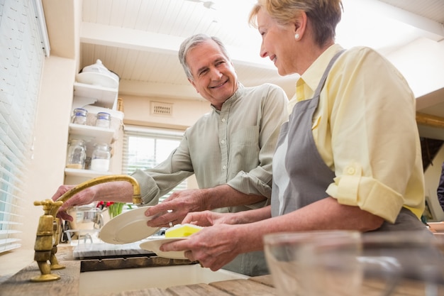 Senior couple washing the dishes at home in the kitchen