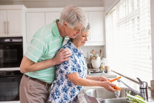 Senior couple washing vegetables at sink