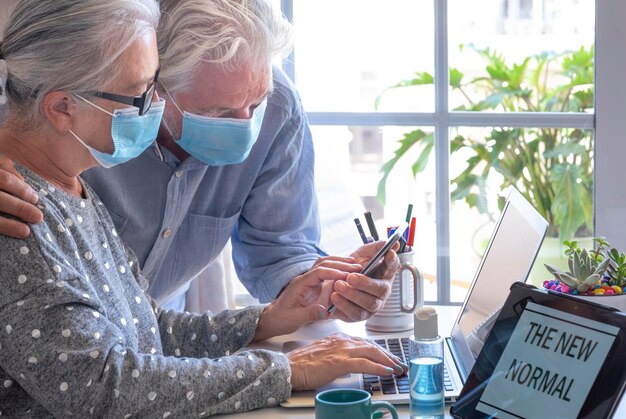 Photo senior couple wearing mask using laptop at home