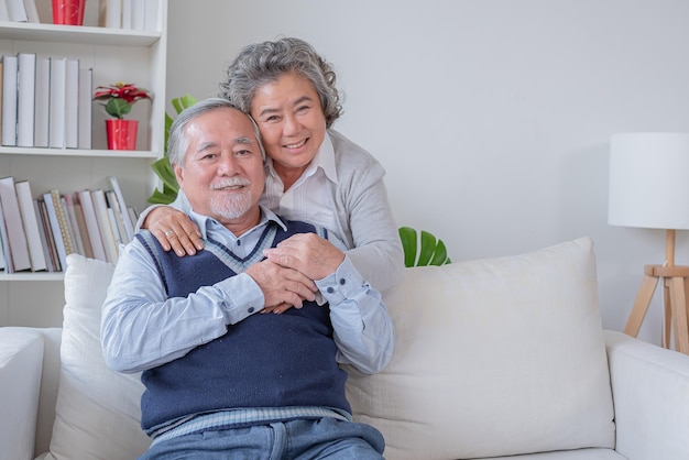 Senior couple wife hugging husband from behind in the house