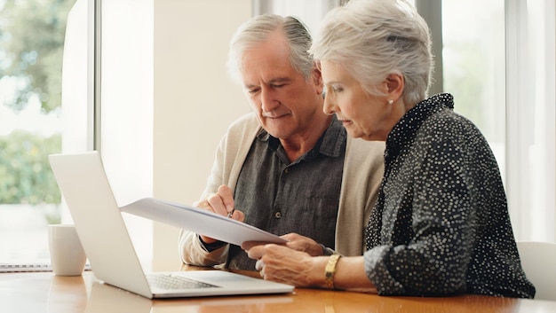senior couple with laptop and budget document paperwork or finances for retirement plan
